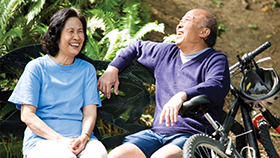 A couple sitting on a bench laughing.